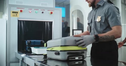 Airport Security Officer Screening Luggage at X-Ray Machine
