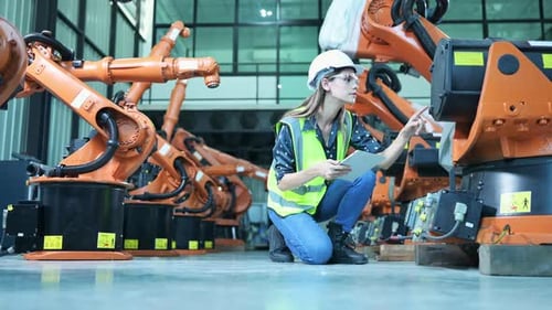 Engineer Inspecting Robotic Arms in Factory