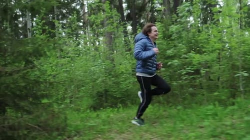 Sportive young man running. Man runs fast in the forest