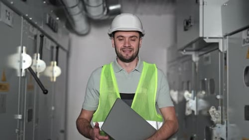 Engineer Holds Laptop in Electrical Control Room