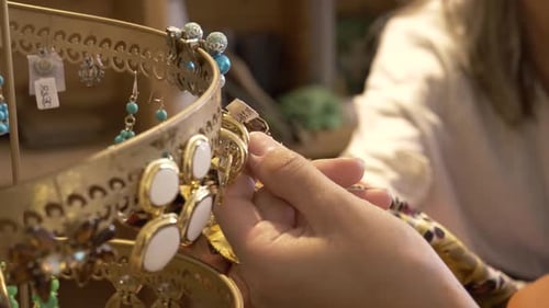 Woman shops for earrings in a jewelry store with slow motion close up