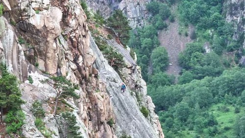 Climber Ascending Steep Rock Face with Safety Rope
