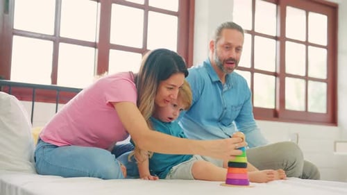 Family Playing with Stacking Rings on a Bed