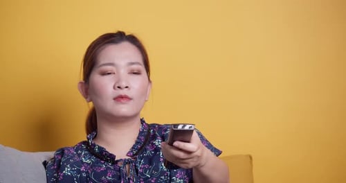 Woman Using Remote Control on Couch Indoors