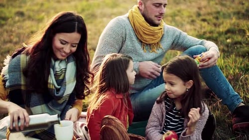 Family enjoying picnic outdoors at golden hour together