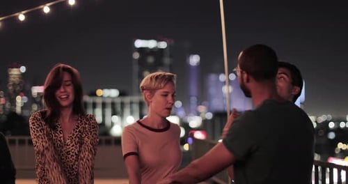 Group of friends dancing on rooftop at night
