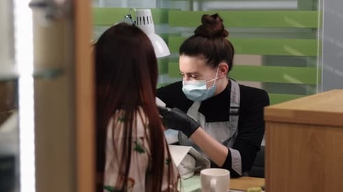 Cosmetician Filing Nails in Salon with Mask and Gloves