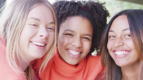 Retrato de amigas adolescentes felizes e diversificadas se abraçando em casa, em câmera lenta