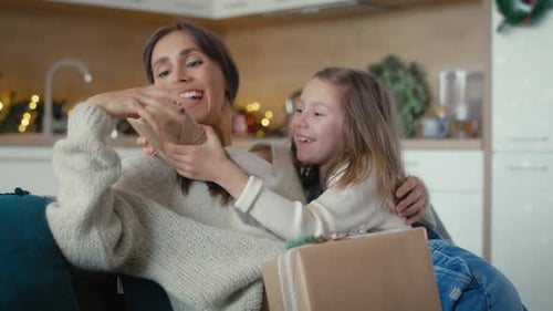 Woman and Child Wrapping Christmas Gifts Together at Home