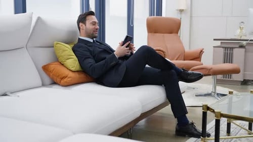 Business Man Celebrates Success Relaxing on Sofa