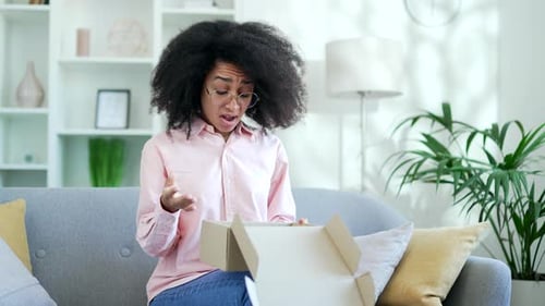 Disappointed Woman Opens Box on Couch