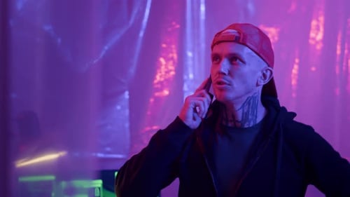 Man in Hoodie Talks on Phone in Lit Room