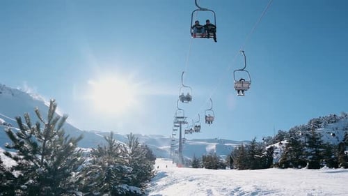 Esquiadores en pendiente nevada y telesilla bajo el brillante sol de invierno