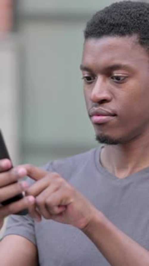 Young Man Using Mobile Phone Outdoors in City