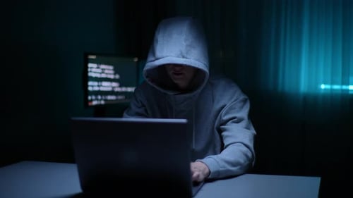 Unbekannter Hacker-Mann, der ein Sweatshirt mit Kapuze trägt und auf der Laptop-Tastatur tippt und