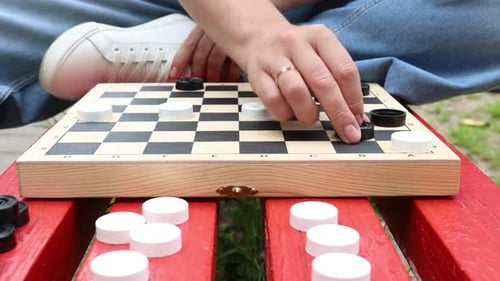 Woman Playing Checkers on a Park Bench on a Sunny Day