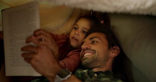 Smiling Father Reading to Daughter Under Blanket Tent
