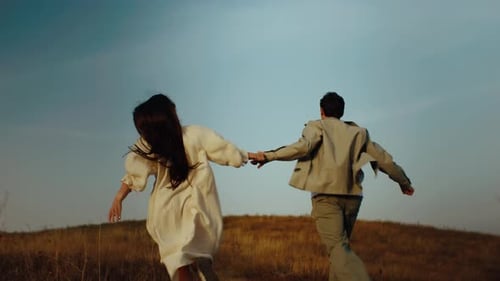 Young Couple Running Through the Hills Love Concept Free Spirit in Nature Beautiful Field on the