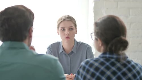 Jeune femme parlant avec des clients au bureau