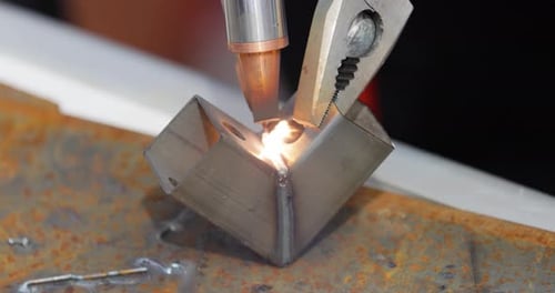 Laser welding machine with hand hold gun. Laser welding is shown in close-up.