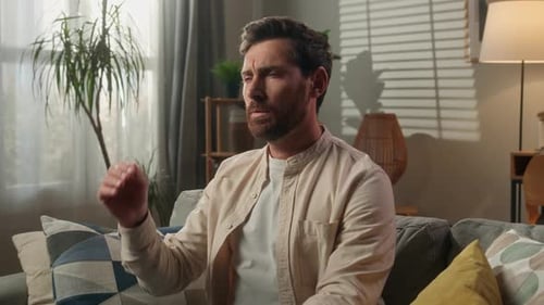 Man Seated on Couch Rubbing Temples