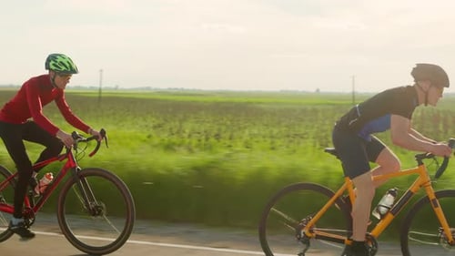 Professional Cyclists Riding on Bikes Along Highway