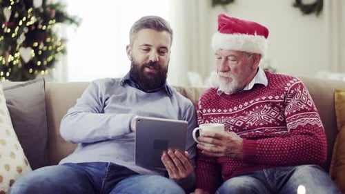 A Senior Father and Adult Son with Tablet Sitting on a Sofa