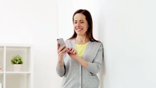 Woman using phone smiles in brightly lit room