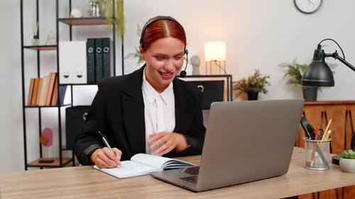 Businesswoman on Video Call Taking Notes at Desk