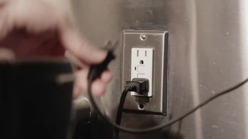 Hand Plugs Cable Into Outlet Socket