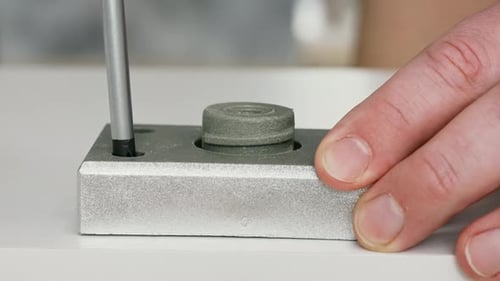 Worker installing furniture cam lock and dowel using specialized tool