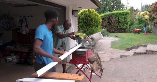 Father and Son Using Table Saw Outside Garage at Home 2024 Years