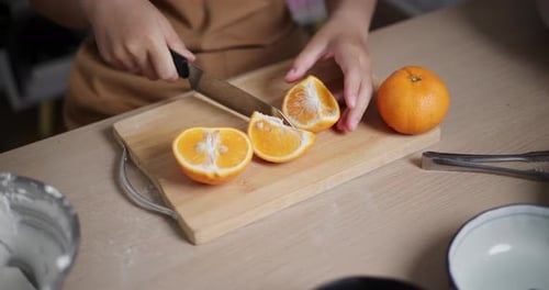 Junge Asiatin schneidet Orangen auf einem Holztisch.