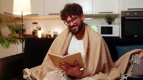 Man Reads Book on Couch in Living Room