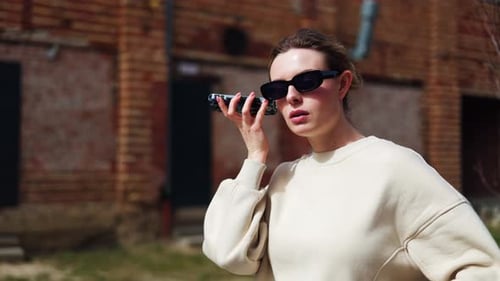 Woman Opening Voice Message on Smartphone and Listening While Standing on Street