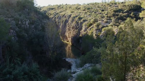 La lumière du soleil traverse une rivière sinueuse qui coule entre les parois rocheuses d'un canyon verdoyant