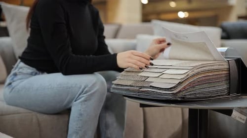 Woman Choosing Upholstery Fabric in Furniture Store