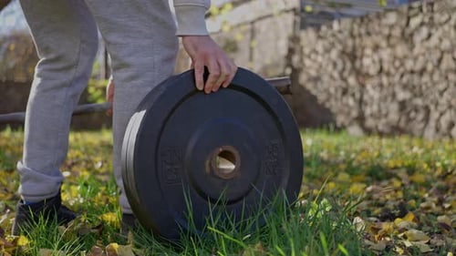 Atleta cargando pesas en un bar en el parque de otoño preparándose