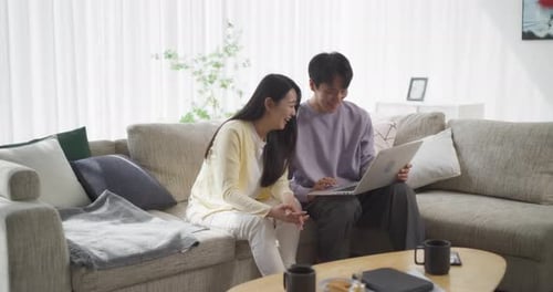 Couple Uses Laptop Together on Couch at Home