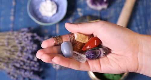 Mulher com pedras preciosas de chakra na mesa de madeira azul, closeup