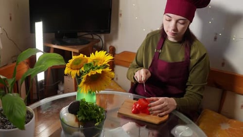Woman Chef Slicing Red Bell Pepper at Table