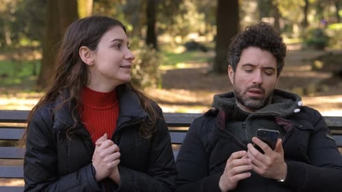 woman becoming angry with boyfriend focused on smartphone while she talking