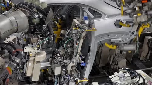 Des robots soudent dans une usine automobile. Plan rapproché.
