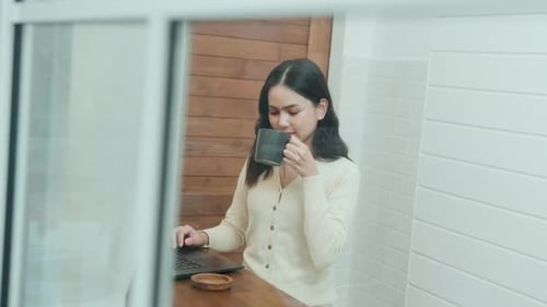 Woman Working on Laptop and Drinking Coffee