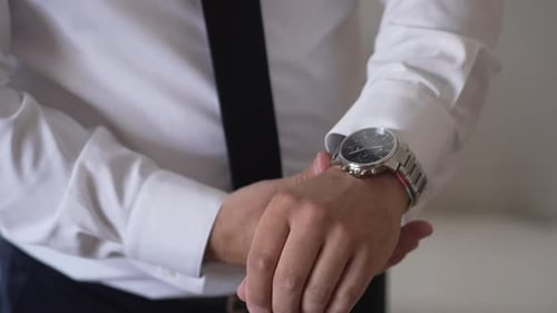 Man Adjusting Sleeves and Checking Watch Indoors