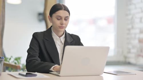 Schockierte junge Geschäftsfrau, die am Laptop arbeitet