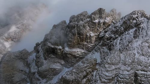 Vue aérienne de haut en bas de montagnes glacées au sommet d'une montagne entourées de nuages profonds dans le ciel