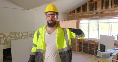 Man Carrying Wood Plank in Unfinished Home