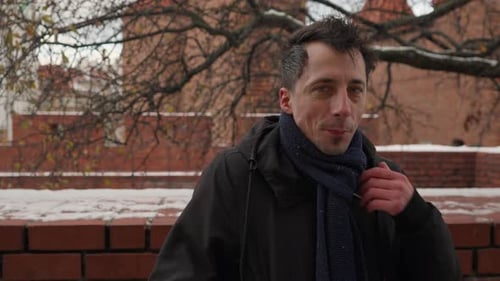 Man Adjusts Scarf in Winter Urban Setting