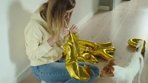 Woman Inflates Letter Balloons on Floor Next to Dog